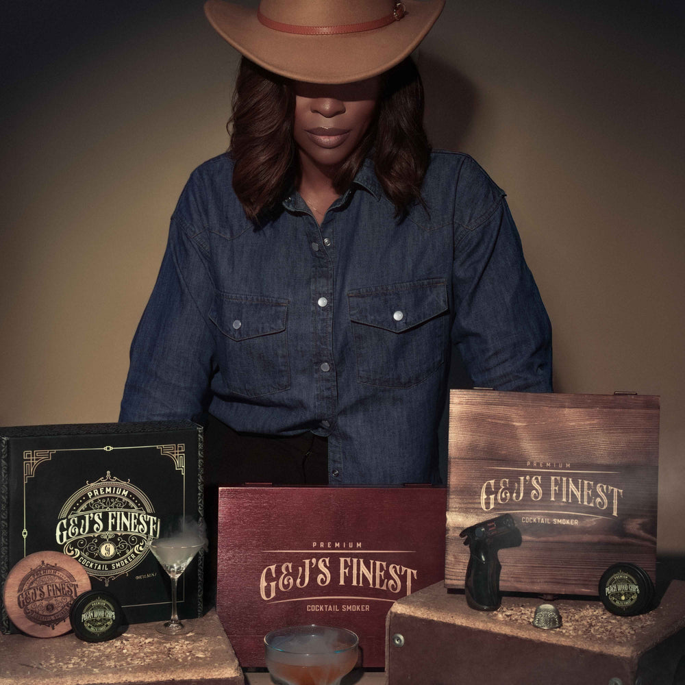 Person wearing a cowboy hat with G&J's Finest products on a wooden table.